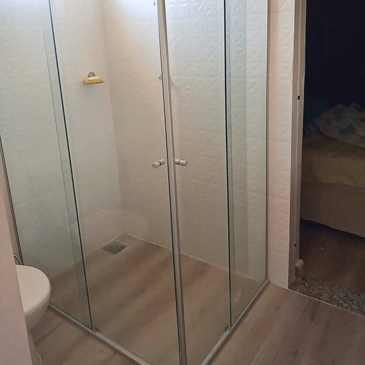 Box de banheiro em vidro temperado com acabamento em alumínio e revestimento cerâmico branco.