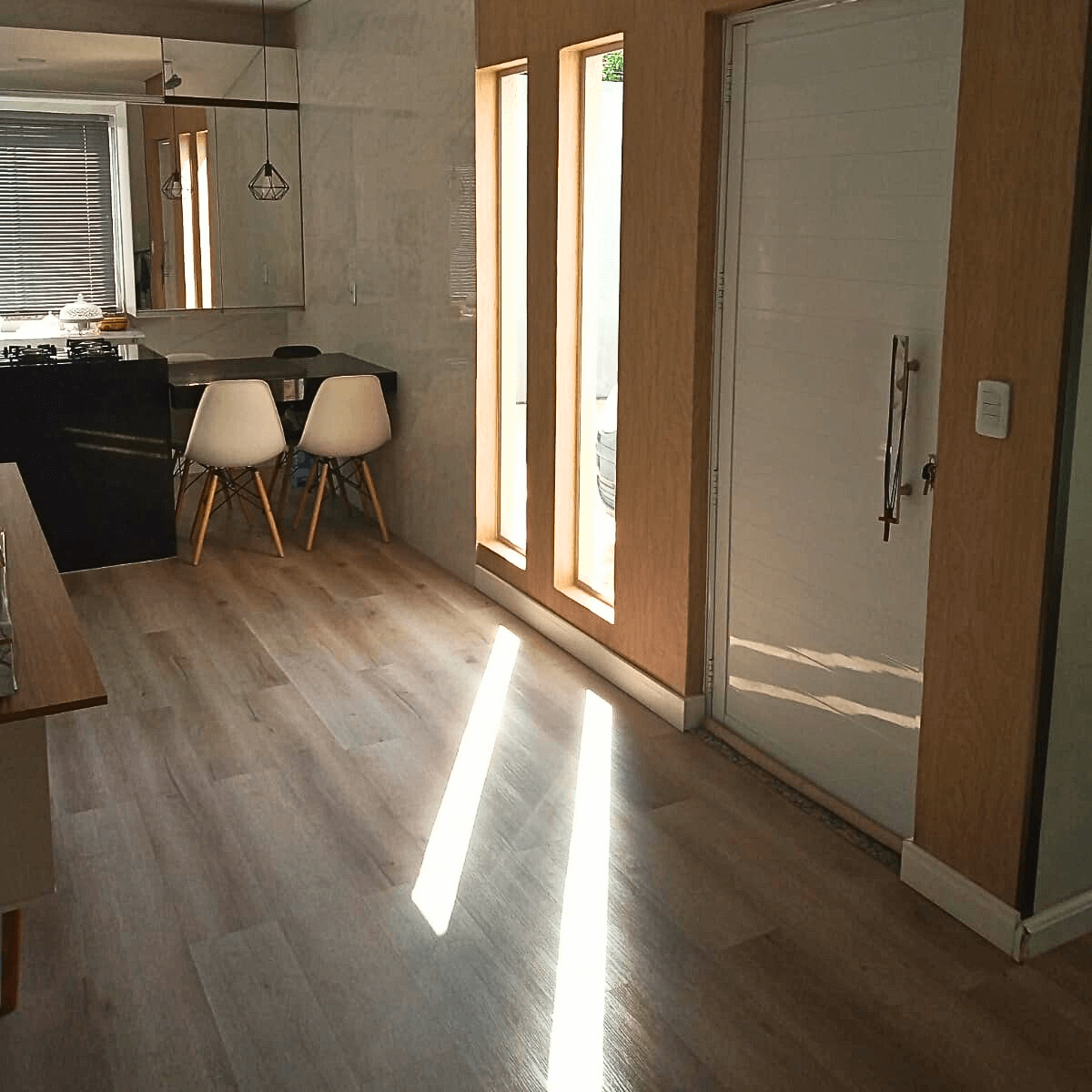 Acabamento impecável de piso laminado em área de circulação e cozinha integrada.