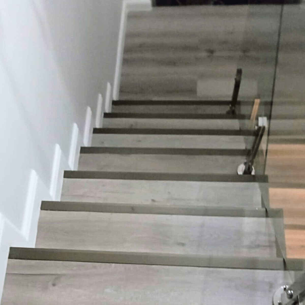 Escada interna revestida com piso vinílico e guarda-corpo de vidro moderno.