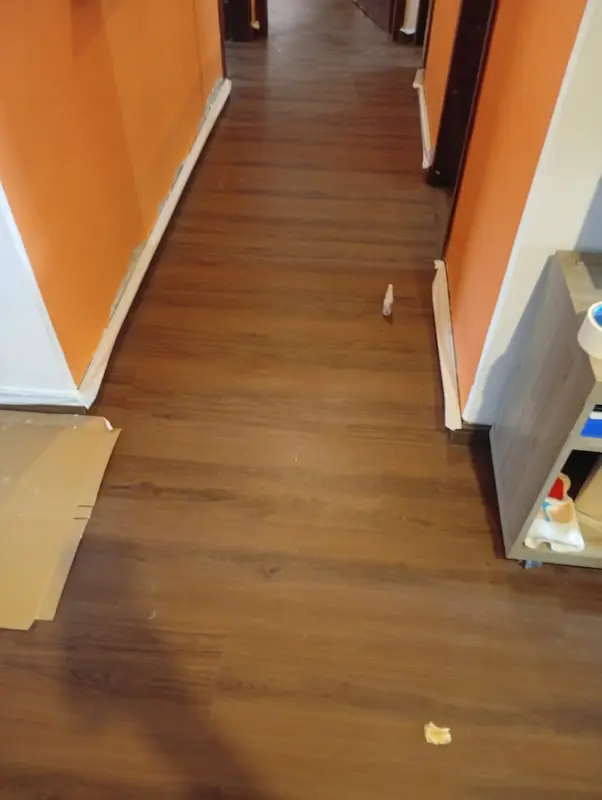 Instalação em andamento de piso laminado em tom de madeira escura em residência de Palmas, Tocantins, serviço realizado pela TEC Floor.