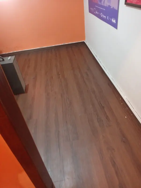Corredor residencial revestido com piso laminado de tom escuro e rodapé branco, proporcionando conforto acústico e térmico em Palmas.