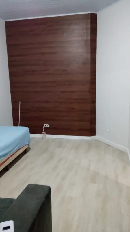 Quarto em Palmas decorado com piso vinílico claro no chão e revestimento laminado escuro formando um painel de parede sofisticado.
